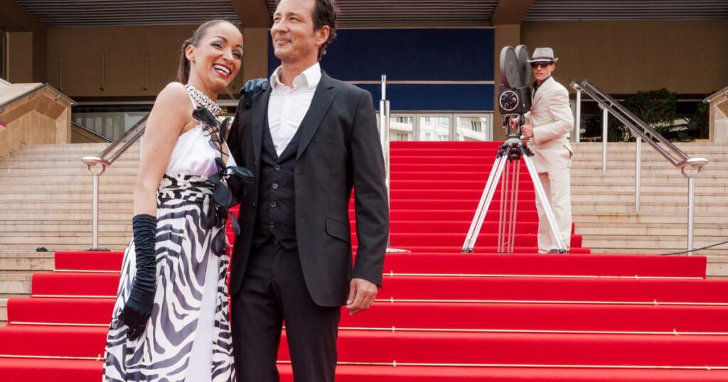 A man and woman standing on red carpet steps at an awards ceremony in Cannes Film Festival.