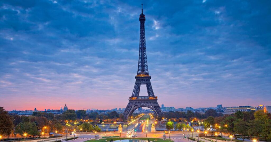 The Eiffel Tower at dusk in Paris, with city lights glowing in the background.