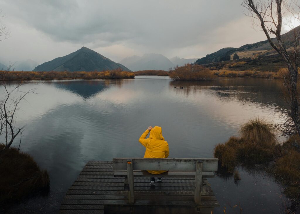 A person sitting on a bench overlooking a lake in Queenstown, New Zealand.