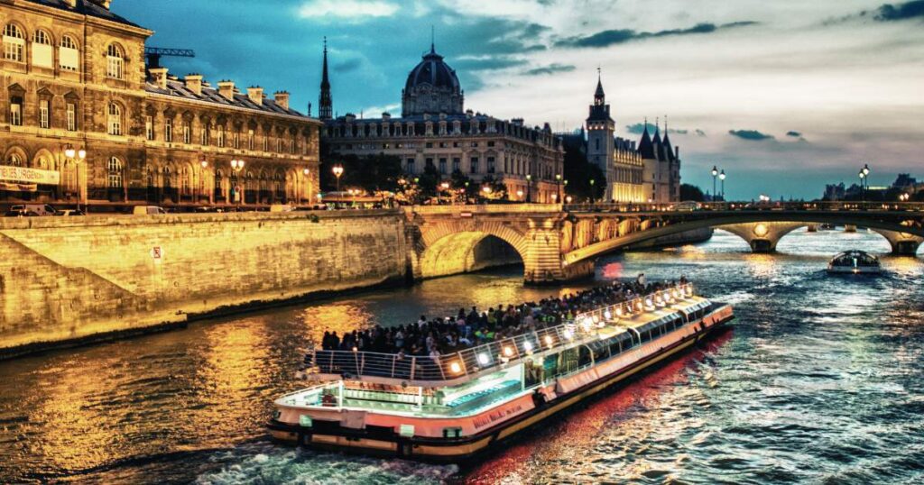 A river boat cruising down the river under the night sky.