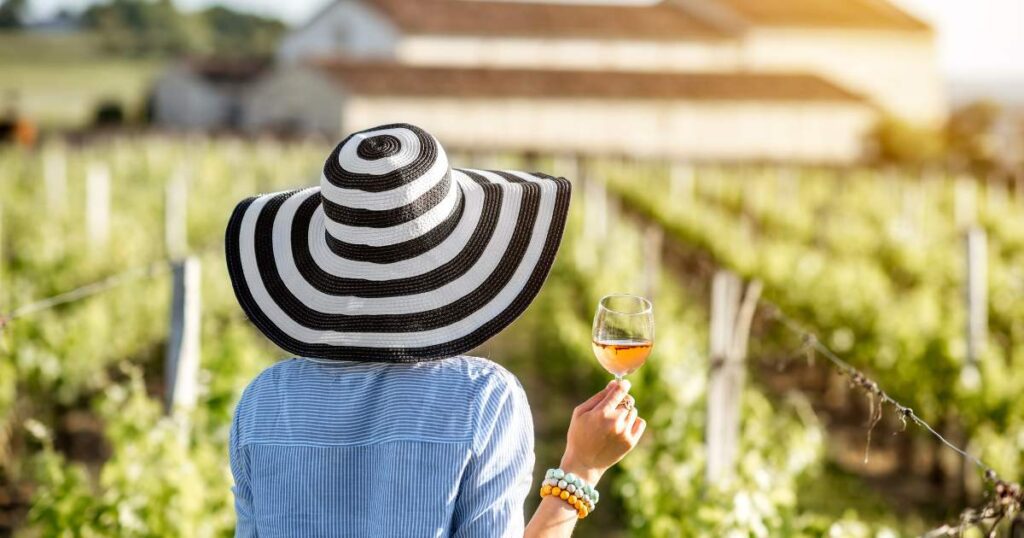 Woman in hat and striped shirt holding wine glass. Bordeaux